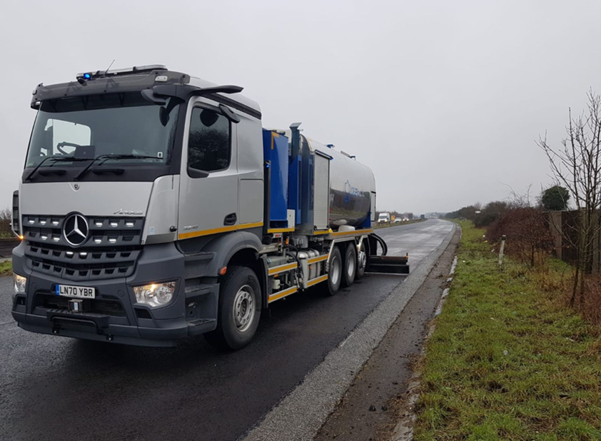 A bond coat sprayer lorry with a rear spray bar, parked at the roadside